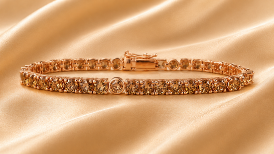 A rose gold tennis bracelet with round-cut yellow diamonds, displayed on a draped beige satin fabric background.
