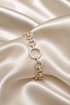 A two-tone gold and white gold bracelet with circular and spiral link designs, embellished with pavé diamonds, displayed on draped champagne satin fabric.