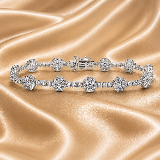 Delicate diamond tennis bracelet with floral cluster detailing arranged on luxurious golden silk fabric.