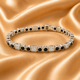 A silver tennis bracelet with alternating round black gemstones and square clear stones, displayed on a draped gold satin fabric background.