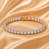 A curved tennis bracelet with baguette-cut clear stones in a silver-toned setting, displayed on draped champagne satin fabric.