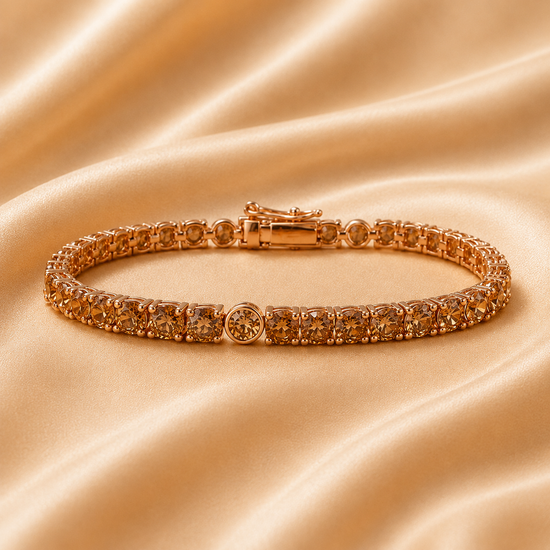A rose gold tennis bracelet with clear round-cut gemstones, displayed on a draped champagne satin fabric background.