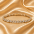 A diamond tennis bracelet with round-cut clear stones set in a silver-toned metal, displayed on a draped champagne satin fabric background.