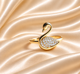 Gold swan-shaped ring with diamond details on a light background