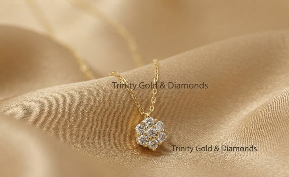 A gold flower-shaped pendant necklace with clear stones, resting on draped champagne-colored satin fabric. The brand name &